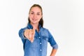 Portrait of beautiful woman in blue jeans shirt pointing her finger and looking at camera on white background. Select focus on Royalty Free Stock Photo