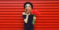 Portrait of beautiful woman with bouquet of red rose flowers in black round hat on background Royalty Free Stock Photo