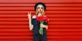 Portrait of beautiful woman with bouquet of red rose flowers in black round hat on background Royalty Free Stock Photo