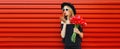 Portrait of beautiful woman with bouquet of red rose flowers in black round hat on background Royalty Free Stock Photo