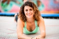 Portrait of beautiful woman in bright sports top lying on trampoline.