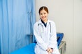 Portrait of beautiful woman doctor sit on hospital bed with stethoscope and look at camera with smiling in emergency toom