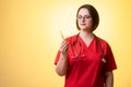 Beautiful woman doctor with stethoscope, wearing red scrubs is looking at the thermometer Royalty Free Stock Photo