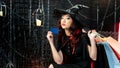 Portrait beautiful woman dressed as witch for Halloween sit holding credit card and shopping bag in halloween theme Royalty Free Stock Photo