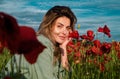 Portrait of a beautiful woman in a field of red poppies enjoys nature. A young woman in a poppy field. Spring girl. Royalty Free Stock Photo