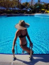 Portrait of a beautiful woman getting out of a swimming pool. beautiful blond hair tanned female model posing by blue Royalty Free Stock Photo