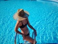 Portrait of a beautiful woman getting out of a swimming pool. beautiful blond hair tanned female model posing by blue Royalty Free Stock Photo