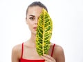 portrait of a beautiful woman with a green leaf in front of her eyes on a light background natural look clear skin Royalty Free Stock Photo