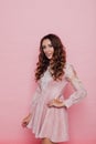 Portrait of a beautiful fashionable woman with hair curls in a pink dress on a pink background Royalty Free Stock Photo