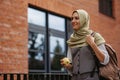 Beautiful woman in hijab standing on city street. Muslim studnet eating apple, going to school. Iran, Afganistan female