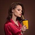 Portrait of beautiful woman holding cup of coffee takeaway in her hand. Brown background Royalty Free Stock Photo