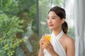 Portrait of a beautiful woman holding a glass of orange juice looking at you sitting at home Royalty Free Stock Photo