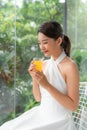 Portrait of a beautiful woman holding a glass of orange juice looking at you sitting at home Royalty Free Stock Photo