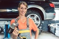 Portrait of a beautiful woman holding an impact wrench while wor