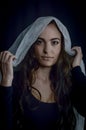 Portrait of a beautiful woman holding a white fabric on her head with a serious look and a timeless attitude