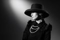 Portrait of beautiful woman in image of famous fashion designer posing in stylish black hat and jacket. Black and white Royalty Free Stock Photo