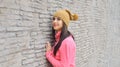 Portrait of a beautiful woman leaning against a wall outdoors.