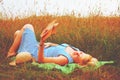 Portrait of beautiful woman lies in the wild flowers field and reading a book. Summer holiday, rest and education concept. Royalty Free Stock Photo