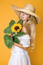 Portrait of a beautiful woman with long blond hair, wearing a white dress, holding sunflowers. Royalty Free Stock Photo