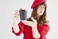 Portrait of Beautiful woman with long hair wearing red hat and sweater holds paper disposable coffee cup. Royalty Free Stock Photo