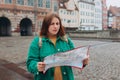 Portrait beautiful woman with paper map on urban street. Young worried female traveler lost in the city using map