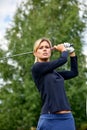 Portrait of a beautiful woman playing golf on a green field outdoors background. The concept of golf, the pursuit of