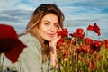 Portrait of a beautiful woman on the poppies meadow. Beautiful girl on a poppy field outdoor. Poppies flowers.