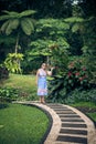 Portrait of beautiful woman posing among blooming asian flowers on Bali island, Indonesia.