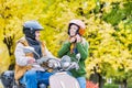 Portrait of beautiful woman putting her helmet on while husband is waiting to drive in park Royalty Free Stock Photo