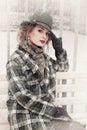 Portrait of a beautiful woman in a retro hat and plaid coat in winter in a snowfall Royalty Free Stock Photo