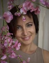 Portrait of a beautiful woman\'s face with a charming smile, near the twigs in pink flowers Royalty Free Stock Photo