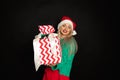 Portrait of beautiful woman in santa hat with toothy happy face, black background, copy space, studio shot, weared in green red Royalty Free Stock Photo