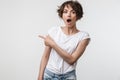 Portrait of beautiful woman with short hair in basic t-shirt rejoicing and pointing finger at copyspace Royalty Free Stock Photo