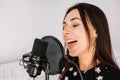 Portrait of beautiful woman sings a song near a microphone in a recording studio. Place for text or advertising