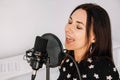 Portrait of beautiful woman sings a song near a microphone in a recording studio. Place for text or advertising