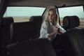 Portrait of beautiful woman sitting on the back seat of the old car and looking at the window thoughtfully.