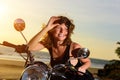 Portrait of a beautiful woman sitting on motorcycle, smiling and holding sunglasses on the forehead Royalty Free Stock Photo