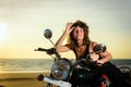 Portrait of a beautiful woman sitting on motorcycle, smiling and holding sunglasses on the forehead Royalty Free Stock Photo