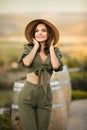 Portrait of beautiful woman smiling with curly hair in hat enjoying at park  by wooden barrel. Autumn Sunset photo Royalty Free Stock Photo