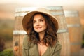 Portrait of beautiful woman smiling with curly hair in hat enjoying at park  by wooden barrel. Autumn Sunset photo Royalty Free Stock Photo