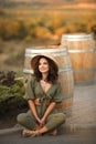 Portrait of beautiful woman smiling with curly hair in hat sitting by wooden barrel at park. Autumn Sunset photo Royalty Free Stock Photo