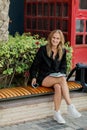 Portrait of a beautiful woman smiling while sitting outside on a bench with a mobile phone in her hands Royalty Free Stock Photo