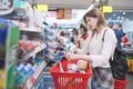 Portrait of a beautiful woman standing in line at the supermarket`s cashier and pulling out the red basket Royalty Free Stock Photo