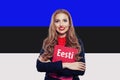 Portrait of beautiful woman student with book against the Estonia flag background