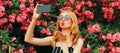 Portrait of beautiful woman taking selfie by smartphone blowing her lips with red lipstick sending sweet air kiss in spring garden Royalty Free Stock Photo