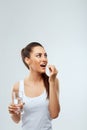 Portrait of beautiful woman taking vitamin pill with glass of fresh water indoors. Smiling girl taking omega 3 fish oil capsule, v Royalty Free Stock Photo