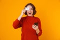 Portrait of beautiful woman using cell phone and credit card while standing isolated over yellow background Royalty Free Stock Photo