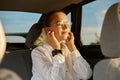 Portrait of beautiful woman is using a earphones for listening music and smiling while sitting on back seat in the car, enjoying Royalty Free Stock Photo