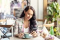 Portrait of beautiful woman using her smarphone in cafe, he reads received messages and follows social networks