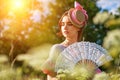 Portrait of a beautiful woman in vintage clothes with a fan in nature on a Sunny day Royalty Free Stock Photo